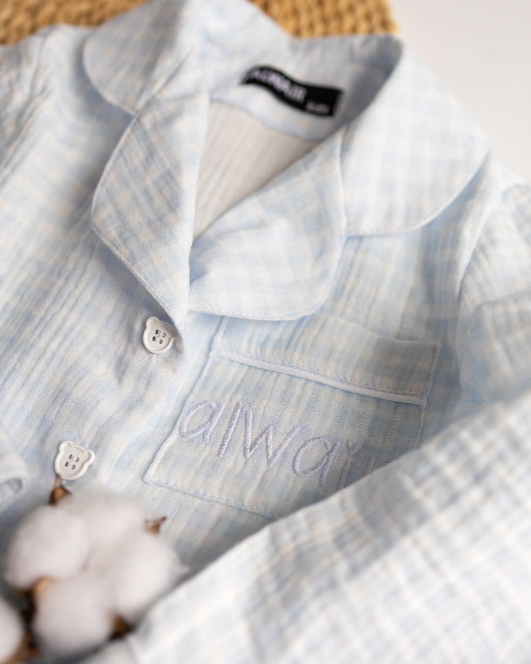Close-up of blue check pajama shirt with embroidered “Alwair” logo on pocket