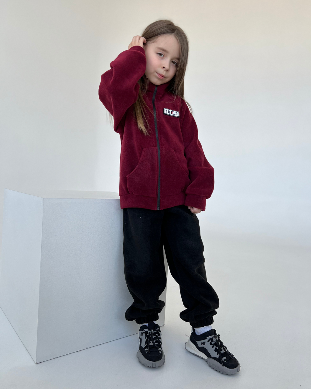 Full-body view of burgundy fleece zip jacket for kids with mood patch