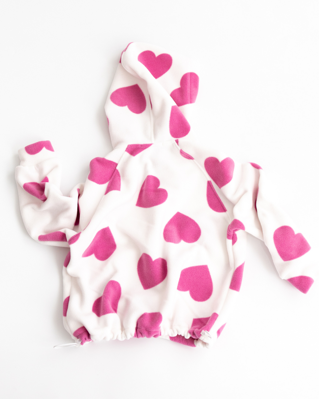 Back view of white fleece hoodie with pink hearts print

