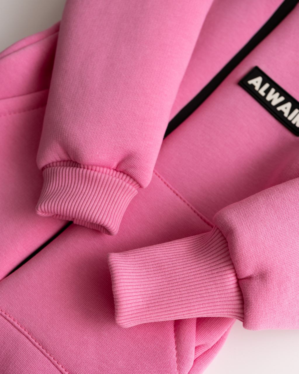 Close-up of ribbed cuffs and sleeve hem on light pink fleece jumpsuit for kids