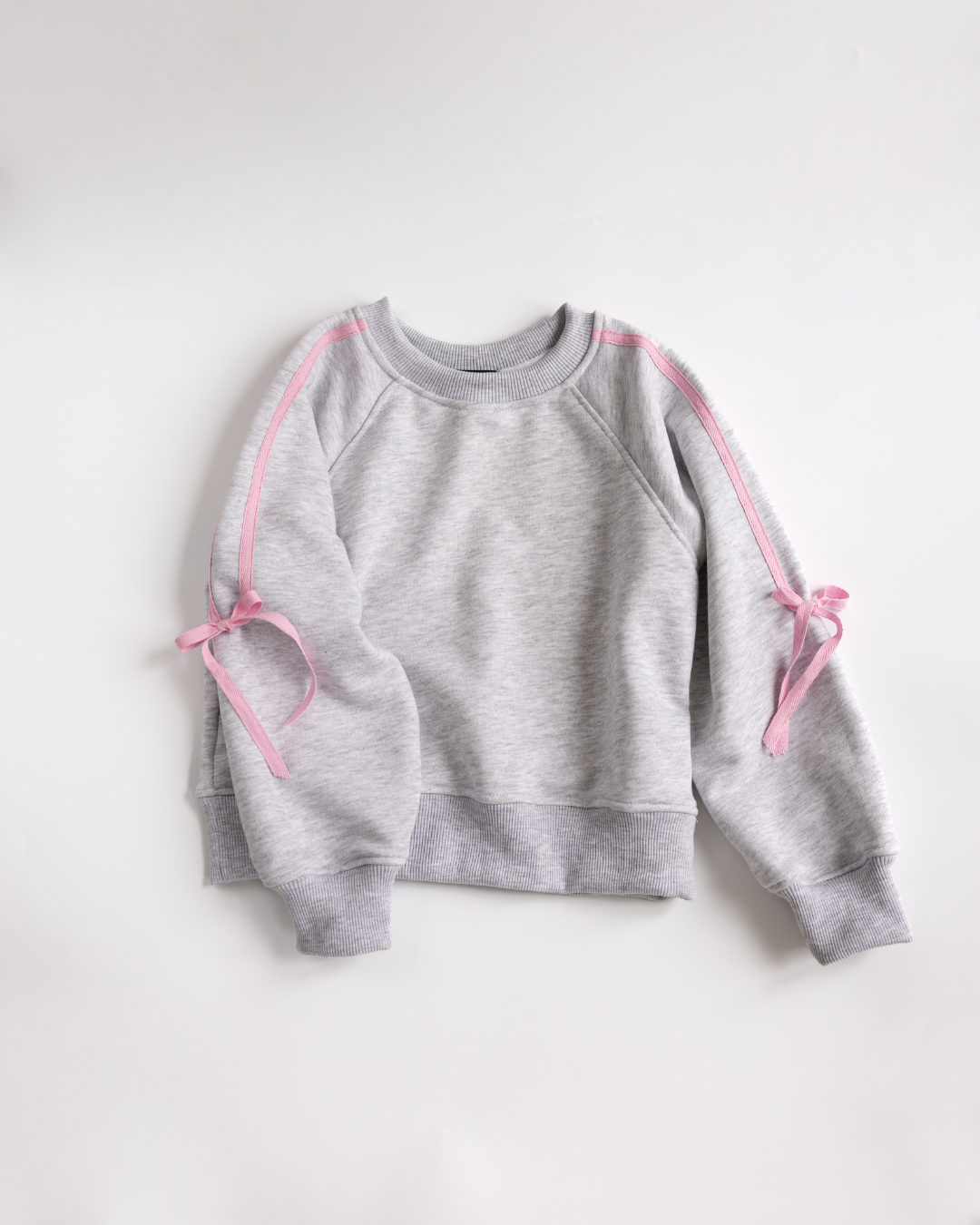 Light grey sweatshirt with pink bow details – laid flat.