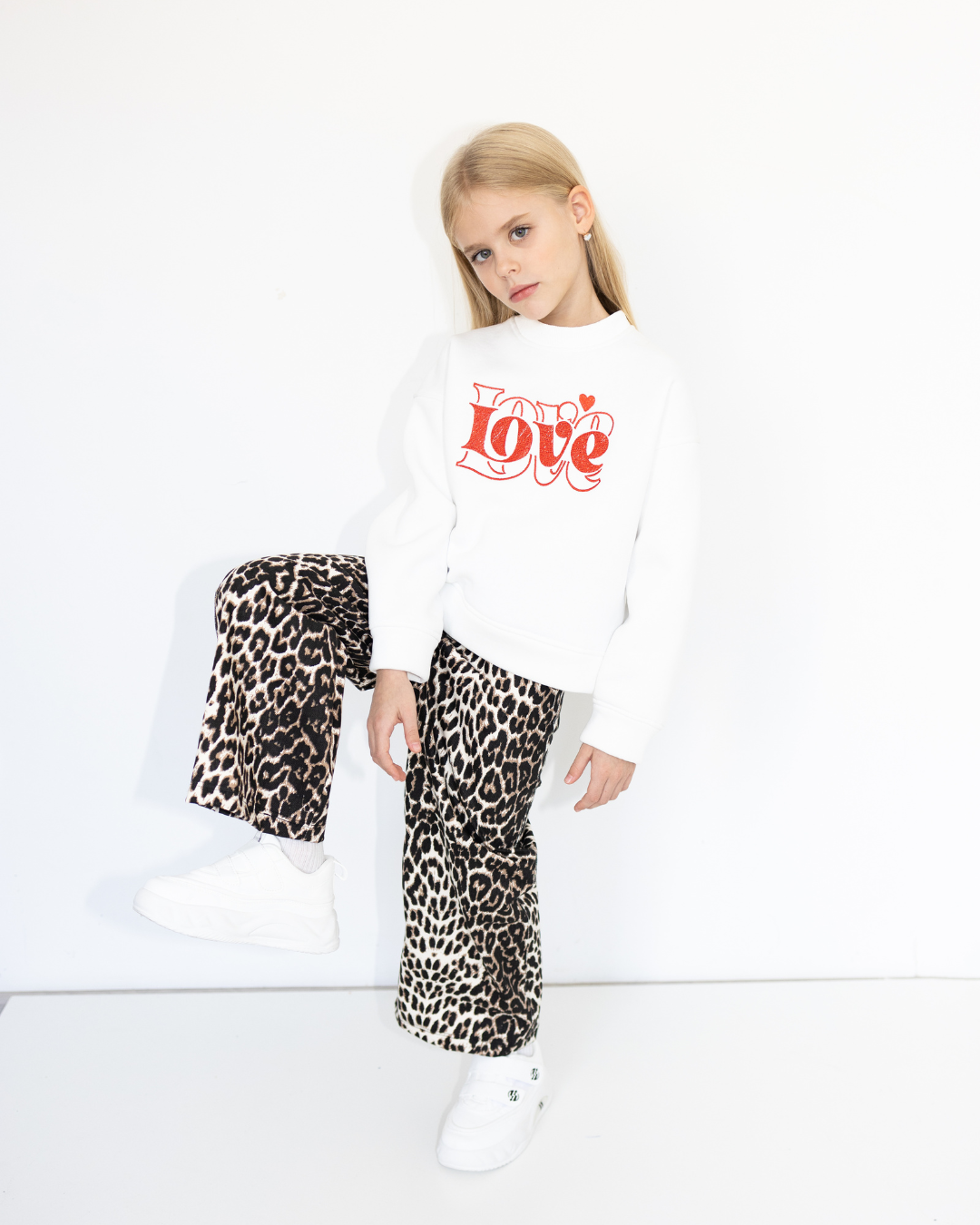 Girl smiling in white Love sweatshirt by Alwair Kids Leo capsule