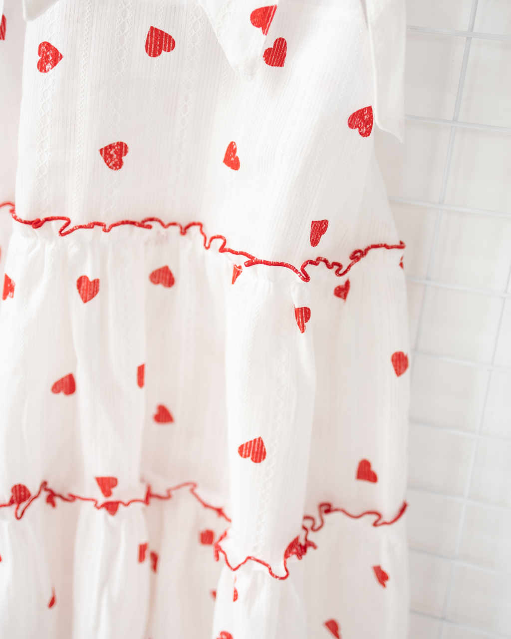 Close-up of ruffled tier and red heart print on white cotton dress – Alwair Kids