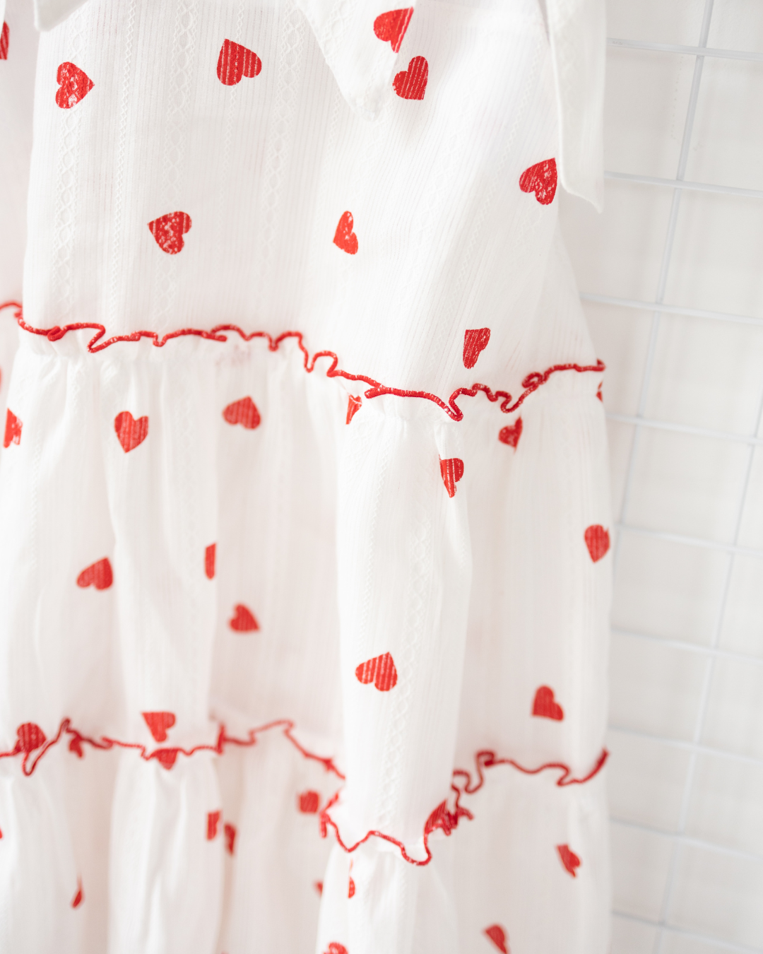 Close-up of ruffled tier and red heart print on white cotton dress – Alwair Kids