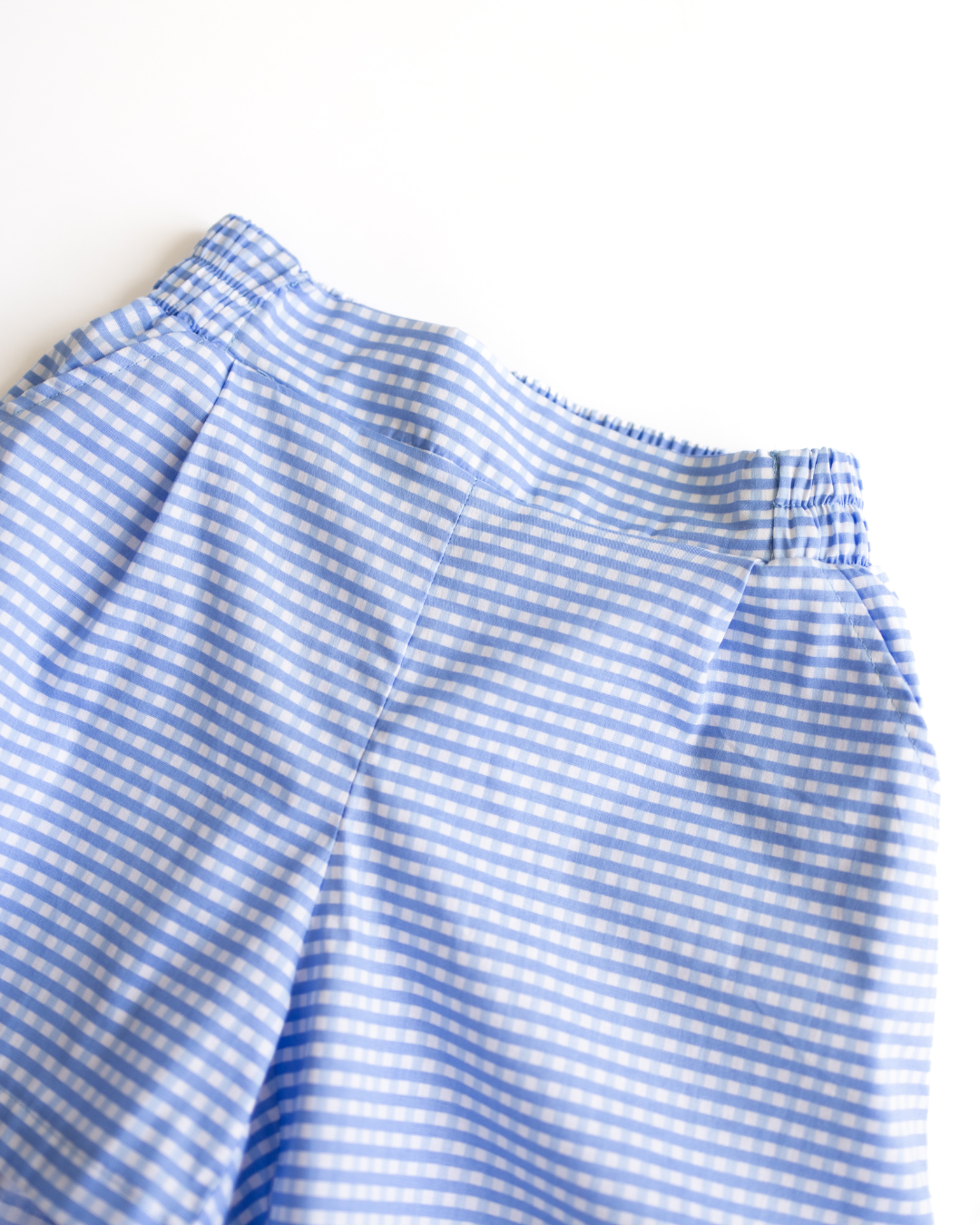 Close-up of soft cotton gingham fabric and waistband on blue summer shorts