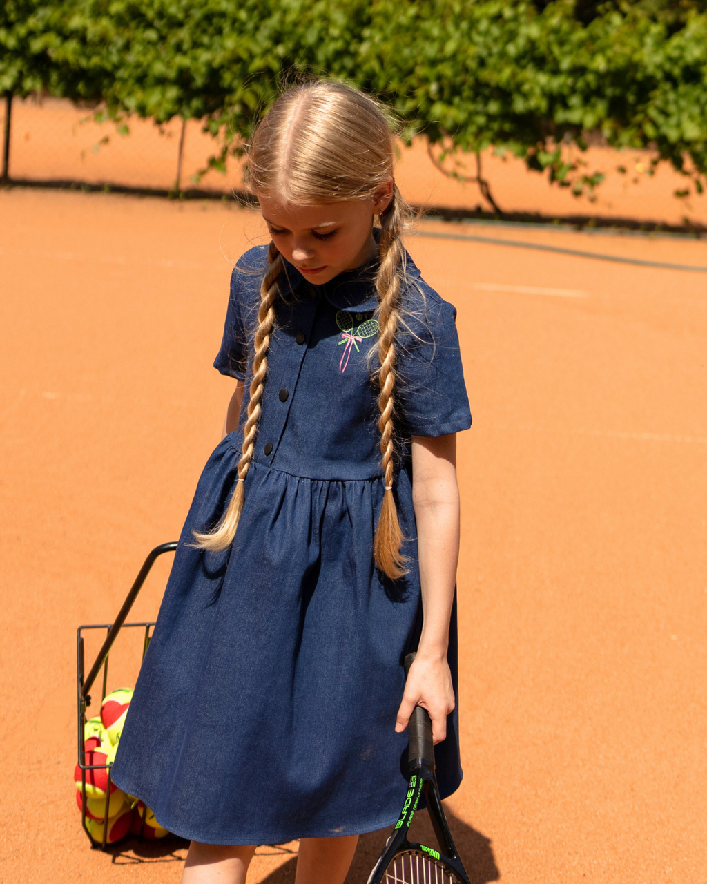 Girl wearing Alwair Kids denim summer dress Tennis Fun on tennis court