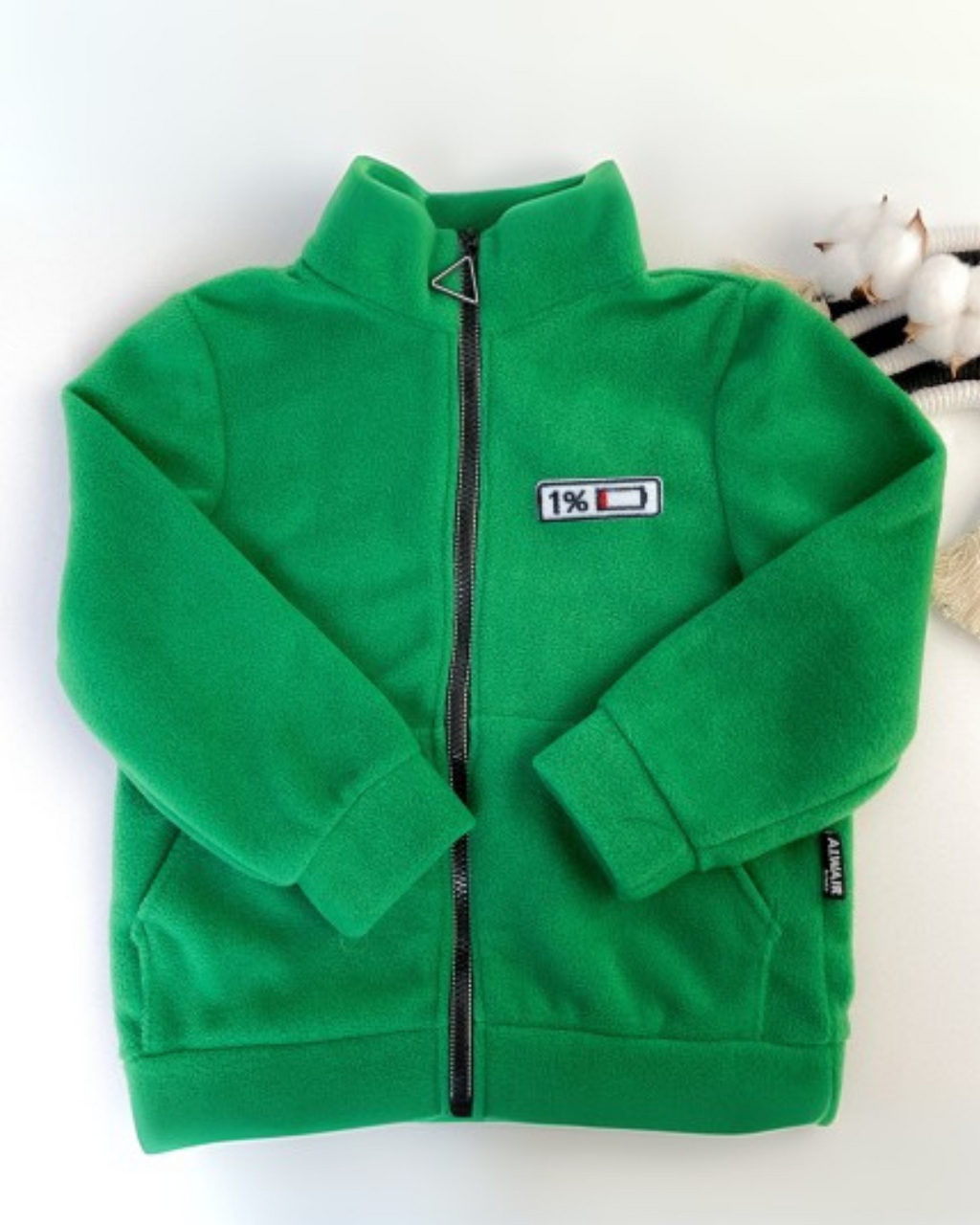 Flat lay of green fleece kids zip jacket with mood patch by Alwair Kids
