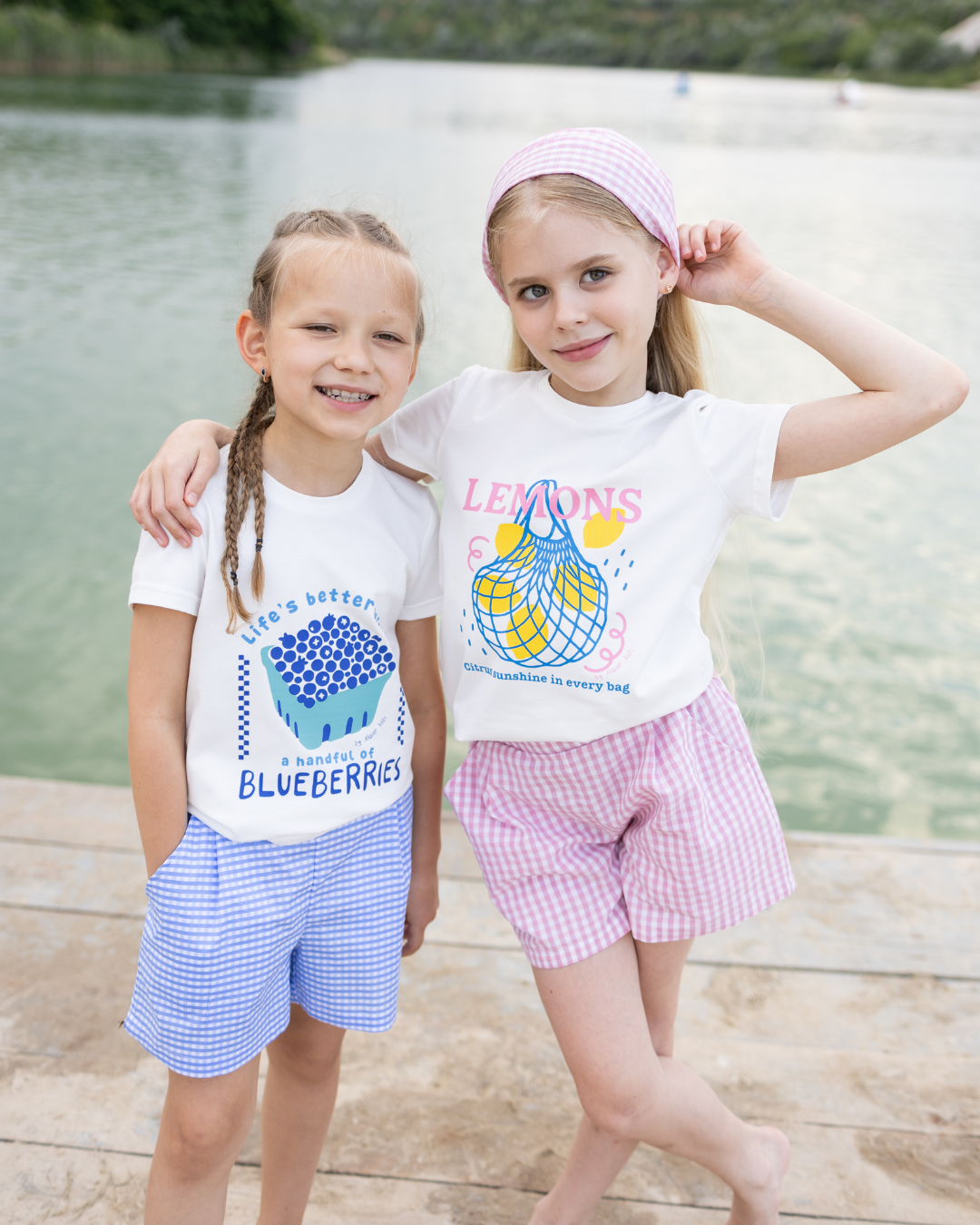 Two girls in Alwair Kids summer outfits Blueberries and Lemons by the lake