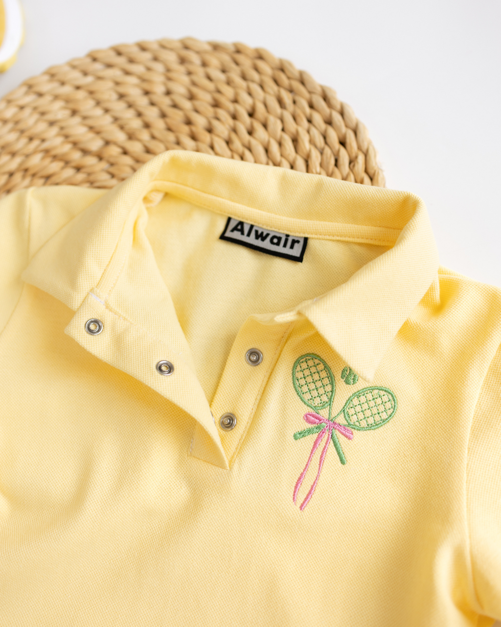 Detail view of collar and snap buttons on yellow kids polo by Alwair Kids