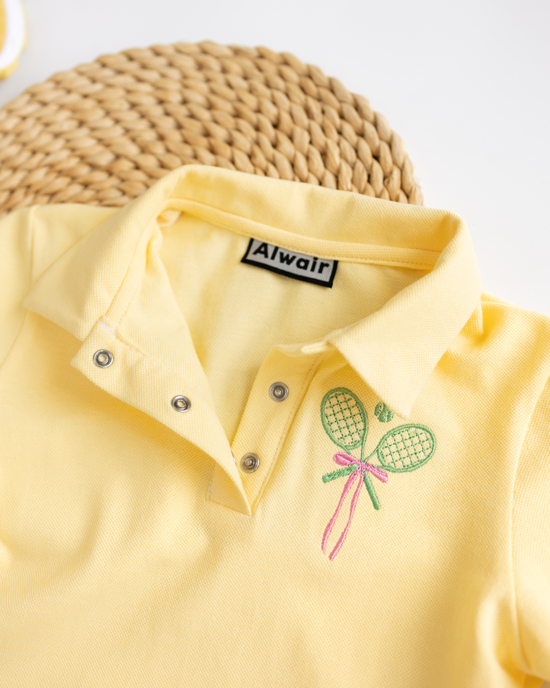 Detail view of collar and snap buttons on yellow kids polo by Alwair Kids