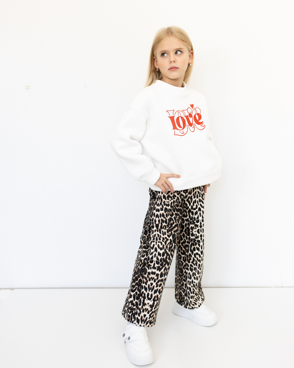 Girl in leopard pants and red sweatshirt by Alwair Kids standing sideways