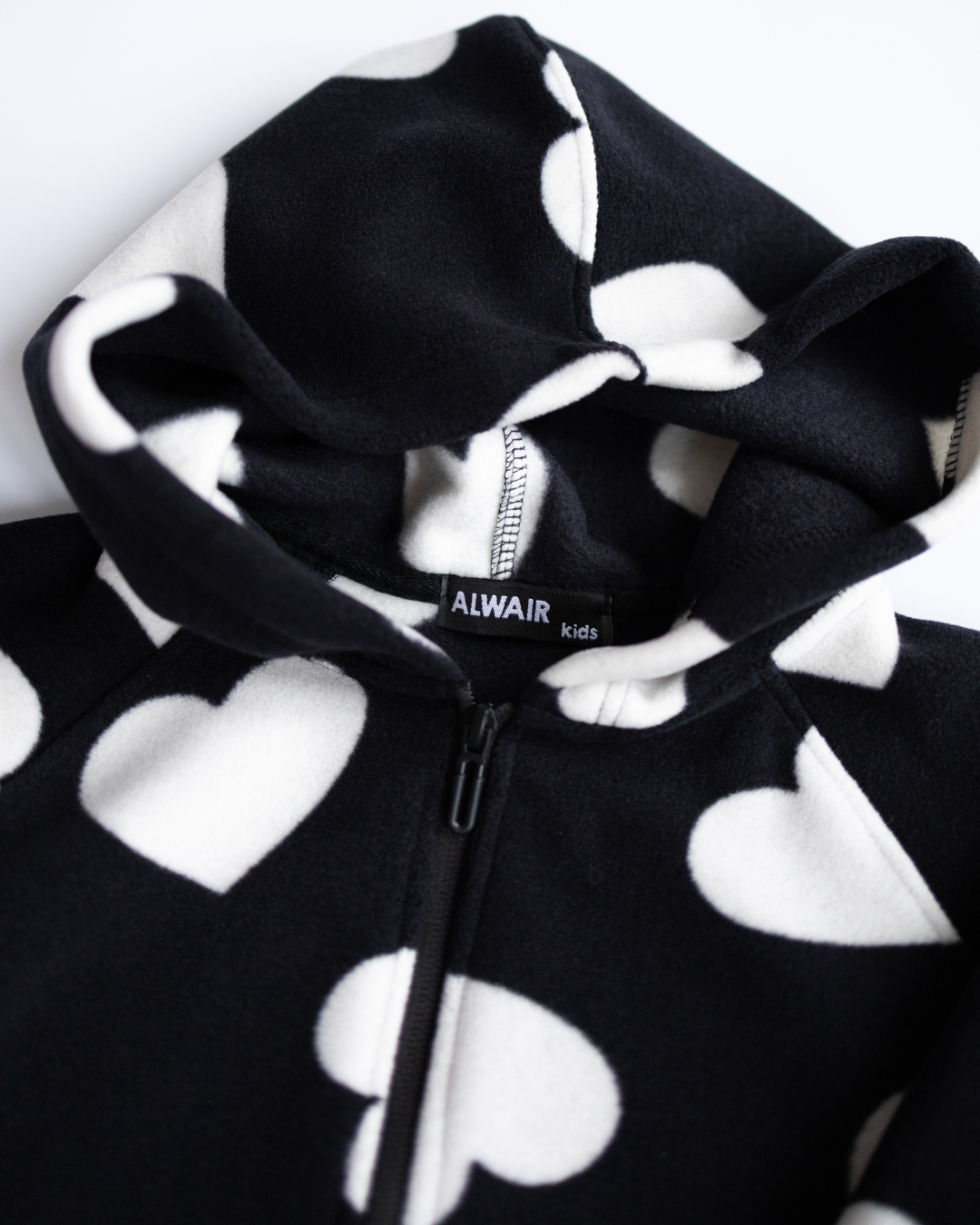 Close-up of hood and Alwair Kids label on fleece hoodie with heart print