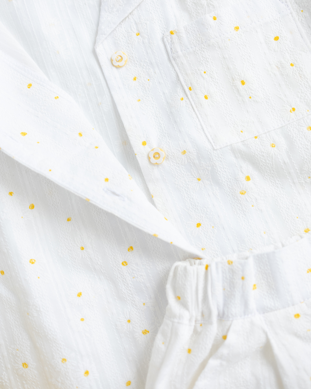 Detail of flower-shaped buttons on white summer shirt by Alwair Kids


