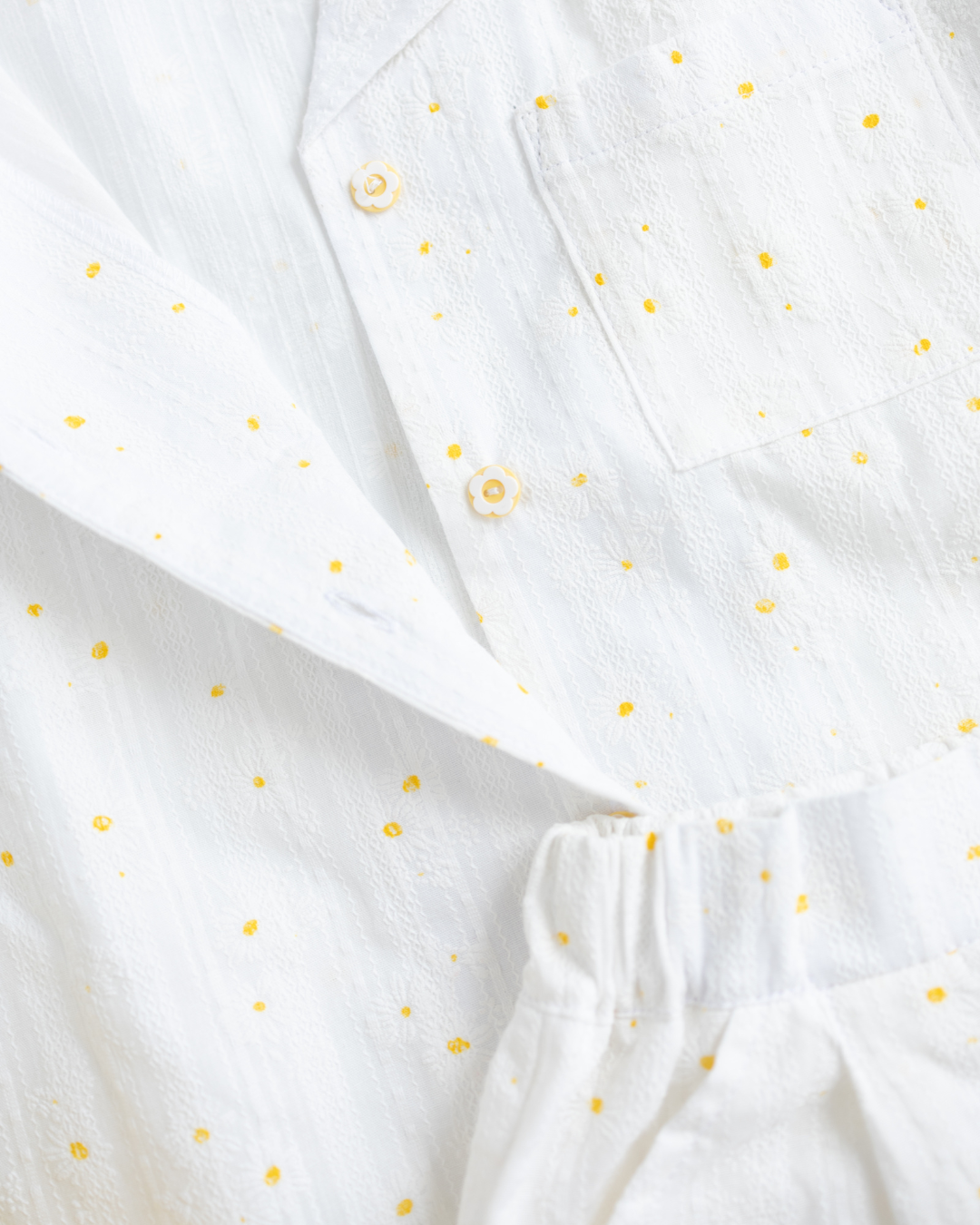 Detail of flower-shaped buttons on white summer shirt by Alwair Kids

