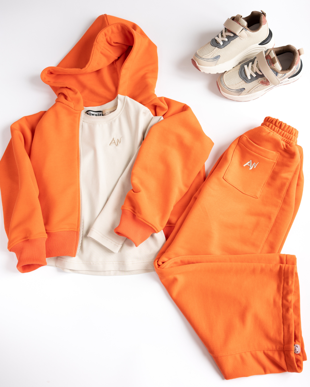 Flatlay of orange three-piece kids tracksuit set with hoodie long sleeve and pants
