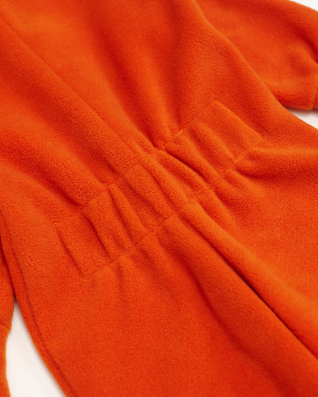 Back elastic waistband detail of orange fleece jumpsuit