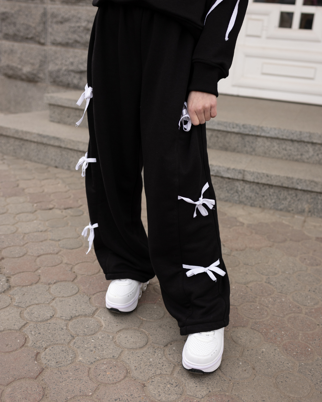 Girl wearing black palazzo pants with white bows by Alwair Kids on urban street