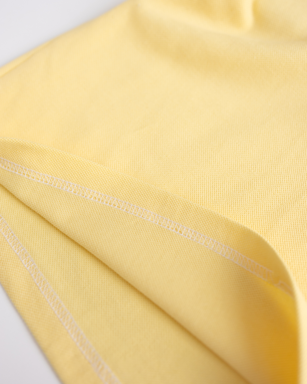 Close-up of fabric texture and inner stitching on yellow Alwair Kids polo