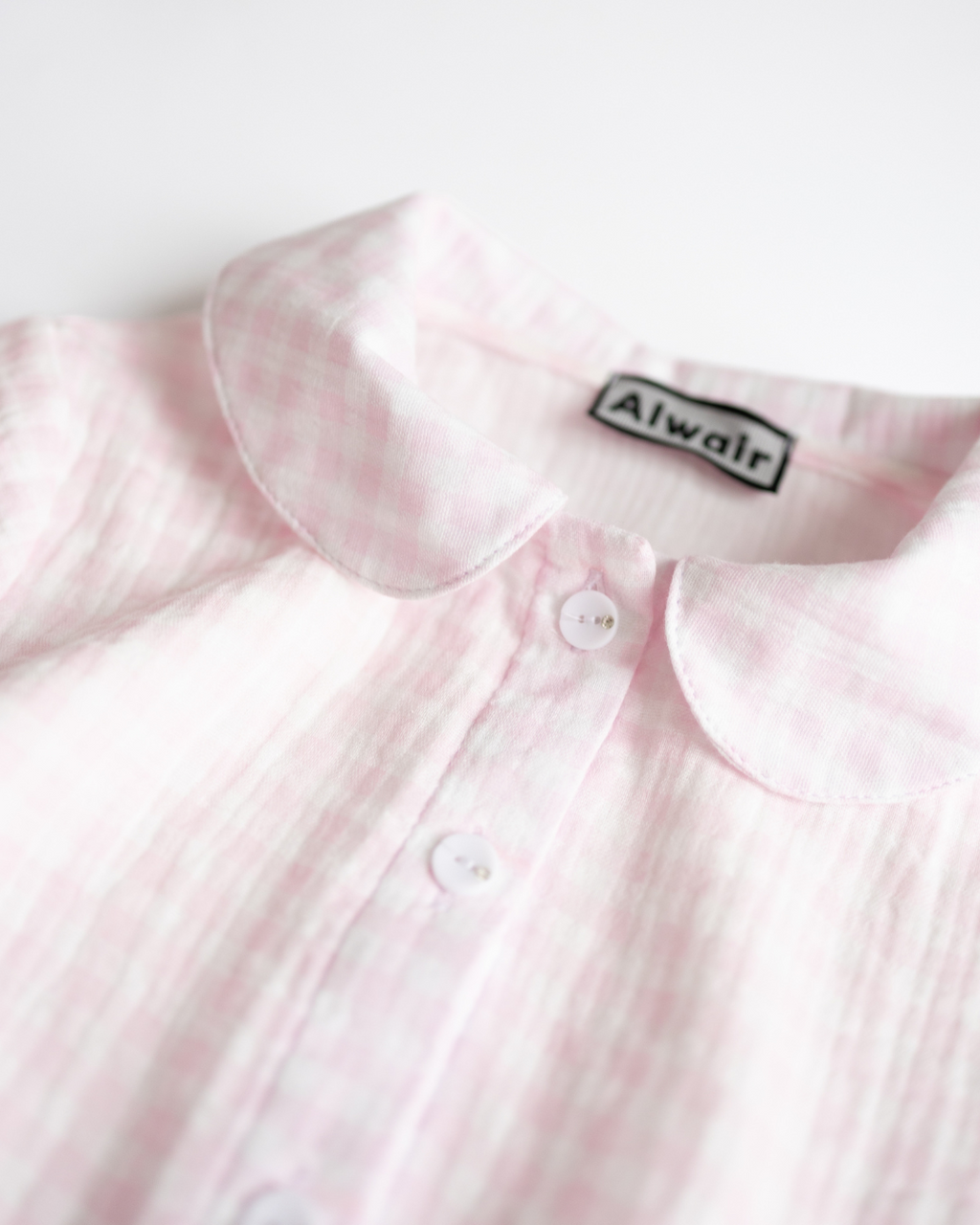 Close-up of pink muslin dress showing fabric texture and button details by Alwair Kids