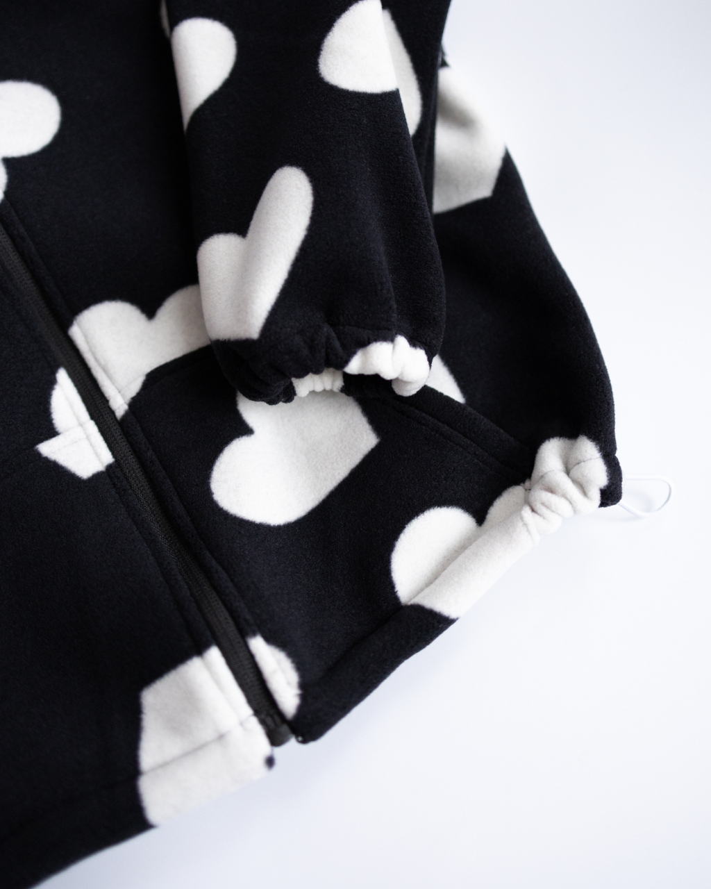 Adjustable hem and sleeve detail of fleece hoodie with heart print
