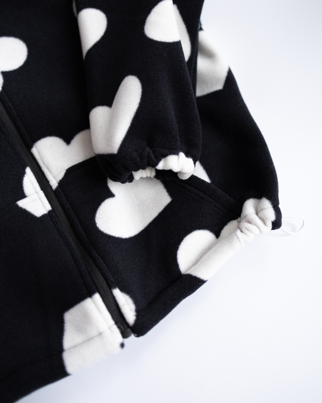 Adjustable hem and sleeve detail of fleece hoodie with heart print