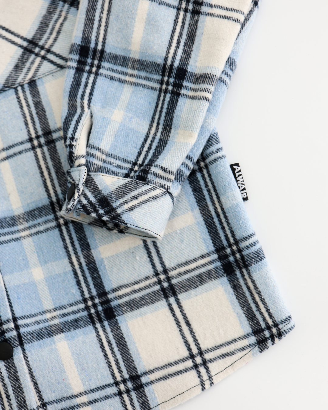 Zoomed detail of black buttons on boys plaid cotton shirt