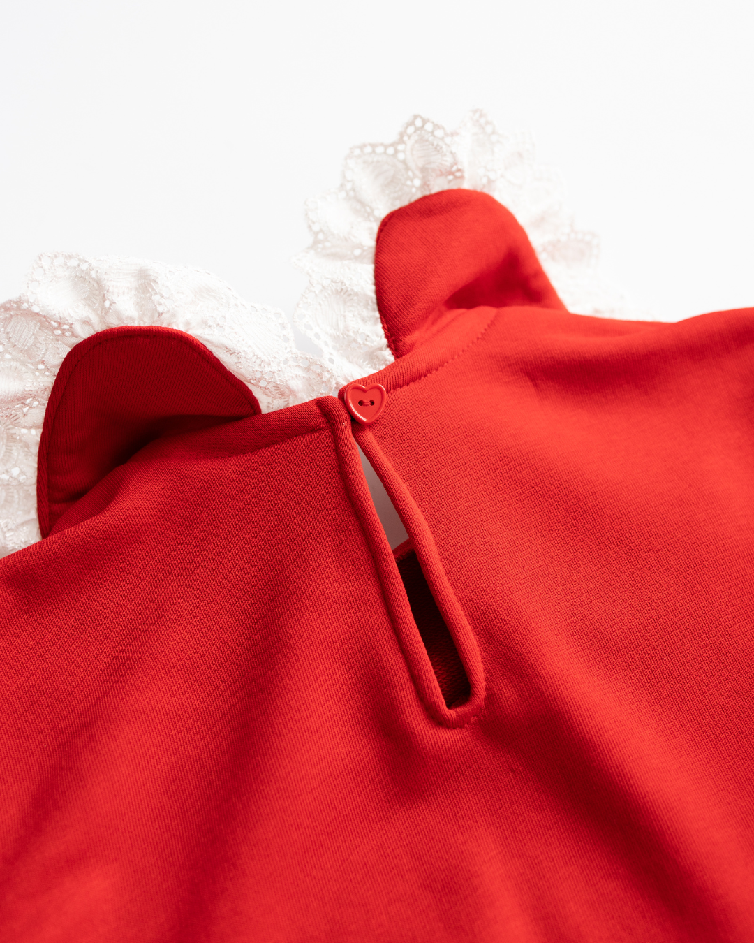 Back button detail on red girls’ sweatshirt with heart-shaped clasp