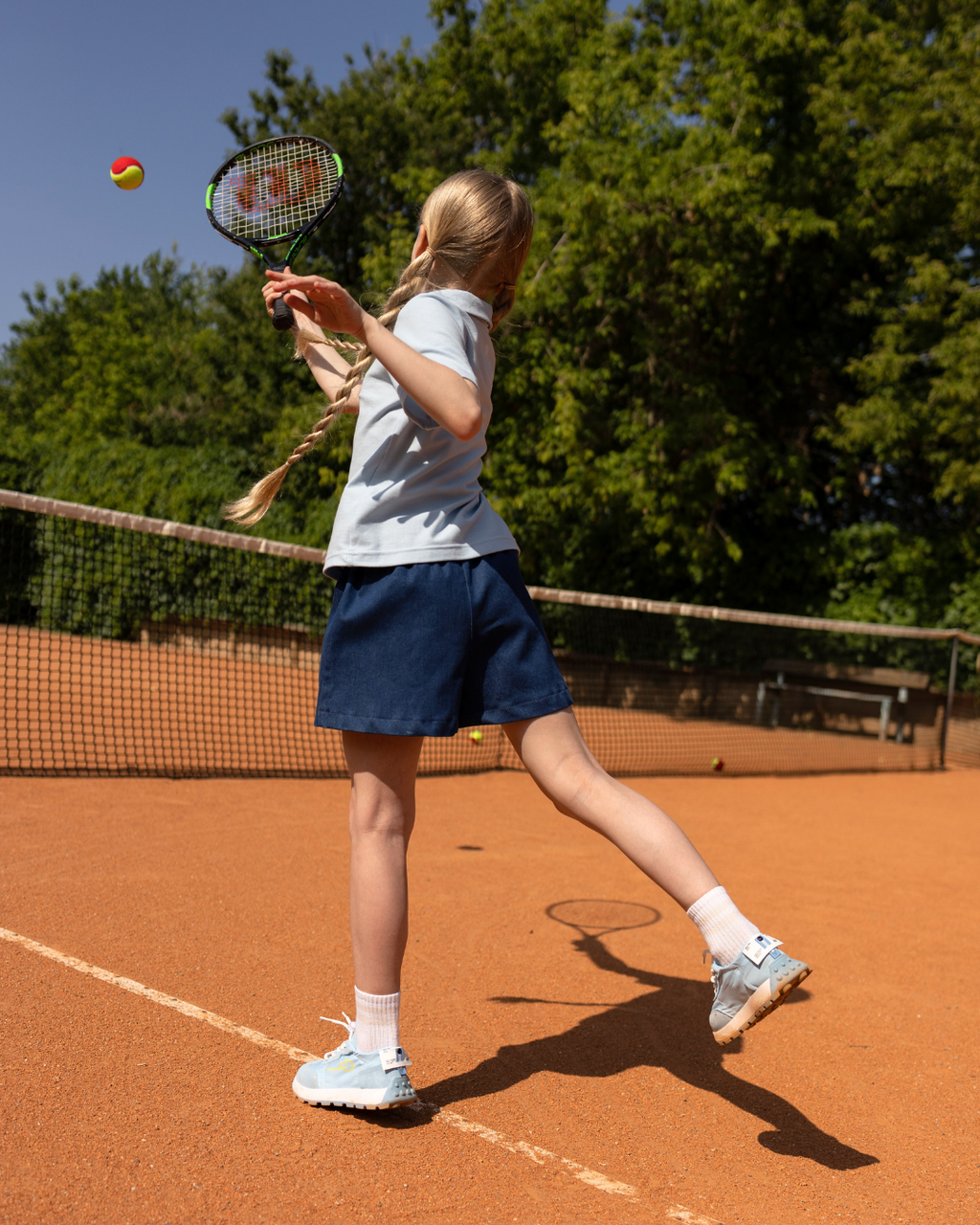 Back view of girl in tennis denim skort by Alwair Kids during tennis throw