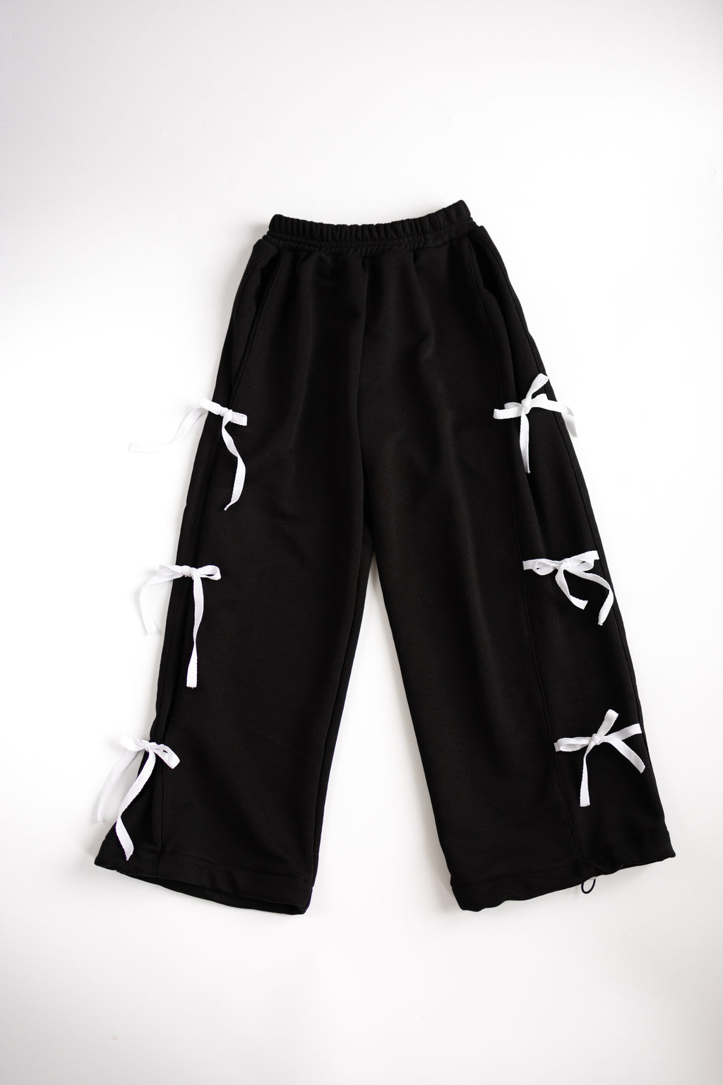 Black cotton pants with white bows flat lay