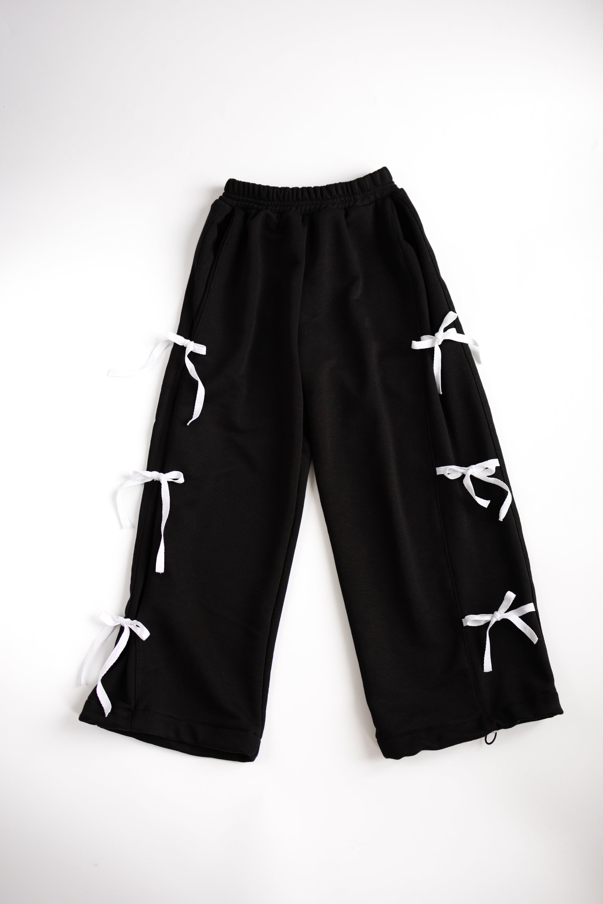 Black cotton pants with white bows flat lay