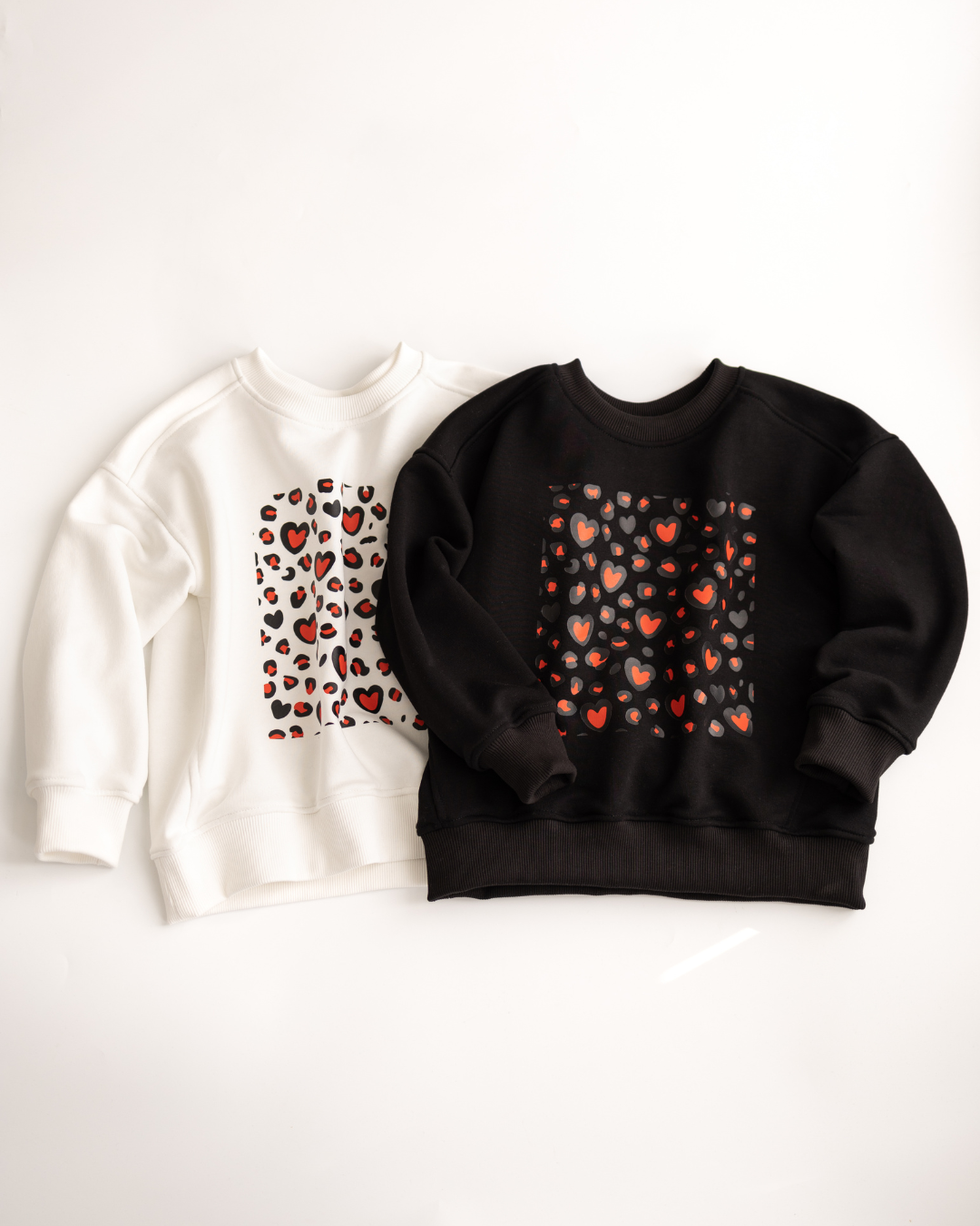 Two kids sweatshirts in white and black with red heart prints