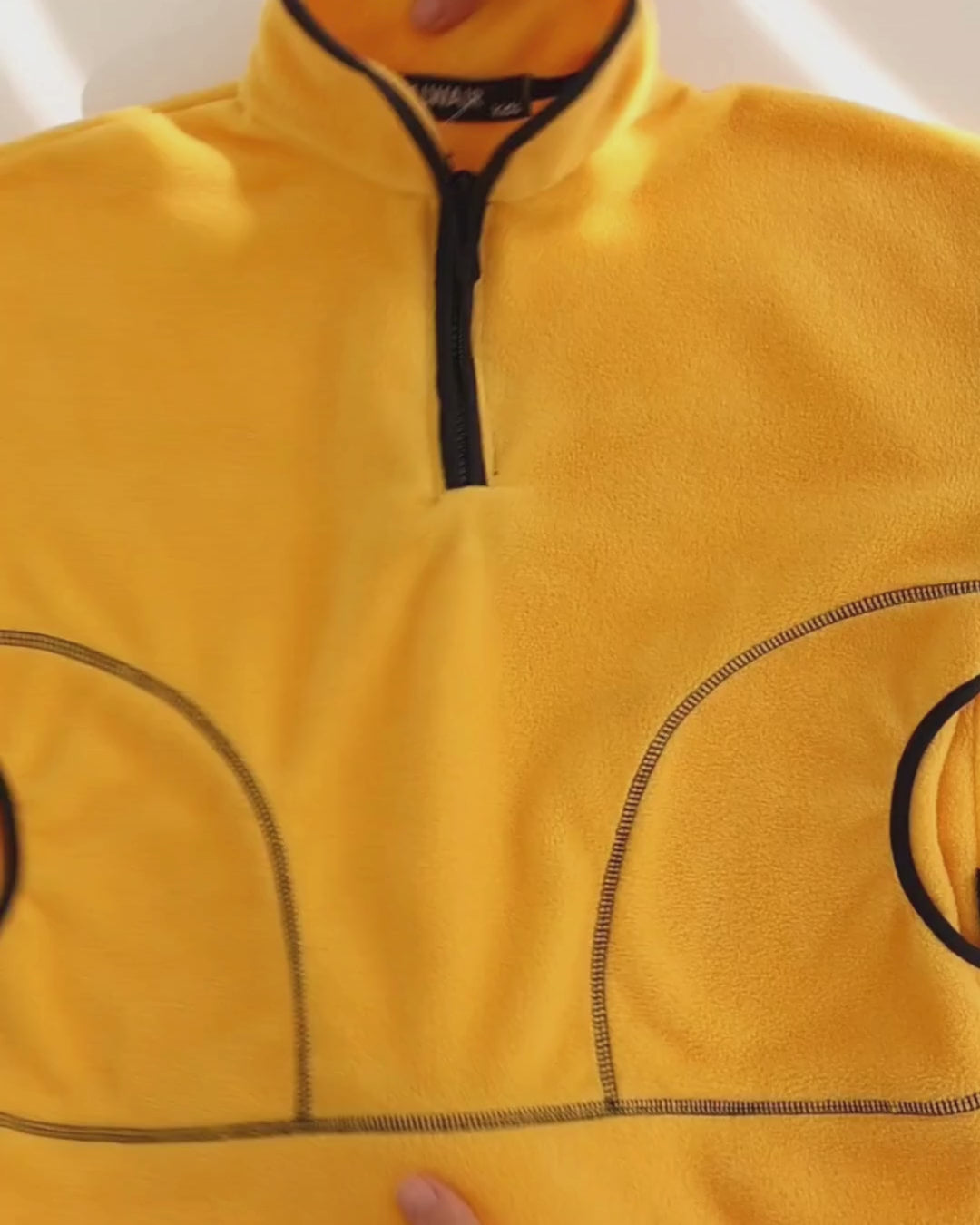 Video showcasing the soft fleece texture and design details of the Alwair Kids pullover in yellow and black. Shows close-ups of stitching and cozy fit